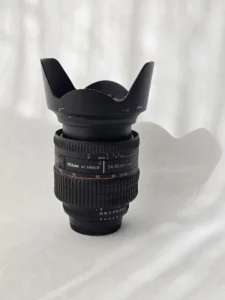 Objectif Nikon 24‑85mm f/2.8‑4D posé sur surface blanche, vue complète avec bagues et repères.