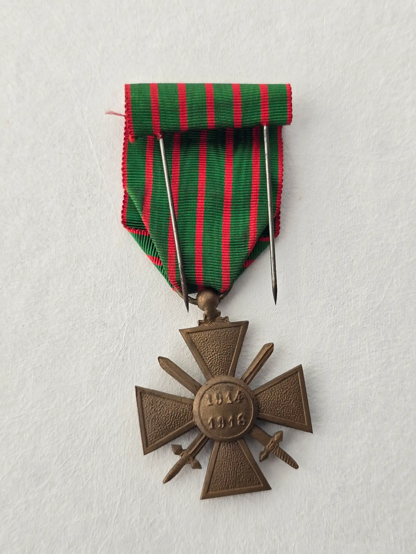 Croix de guerre 1914‑1918 vue de dos avec étoile de bronze cousue, dates 1914‑1918 gravées, ruban vert rayé rouge