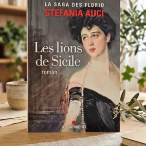 Livre Les lions de Sicile de Stefania Auci posé sur une table en bois avec une tasse de thé et des plantes en arrière-plan. Roman historique publié aux éditions Albin Michel.